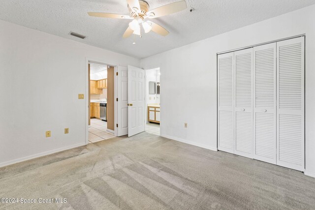 unfurnished bedroom with light carpet, a textured ceiling, a closet, and ceiling fan