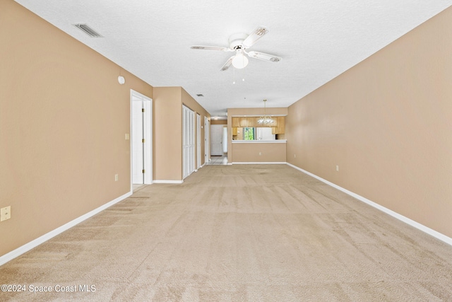 unfurnished living room with light carpet, a textured ceiling, and ceiling fan with notable chandelier