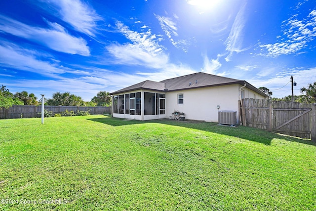 rear view of house featuring a lawn, central AC, and a sunroom