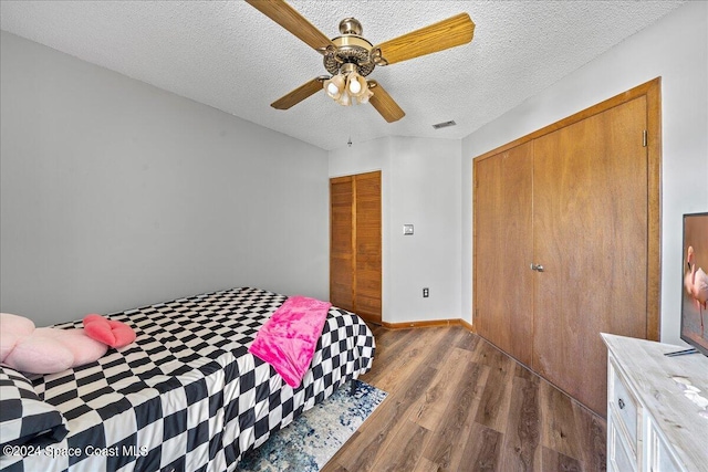 bedroom featuring dark wood-type flooring, ceiling fan, a closet, and a textured ceiling