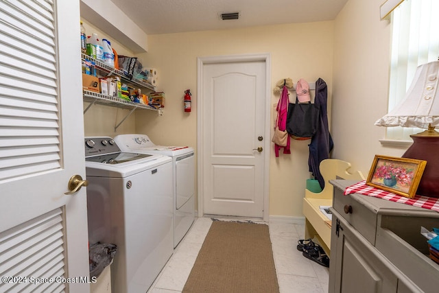 clothes washing area with washer and clothes dryer and light tile patterned floors