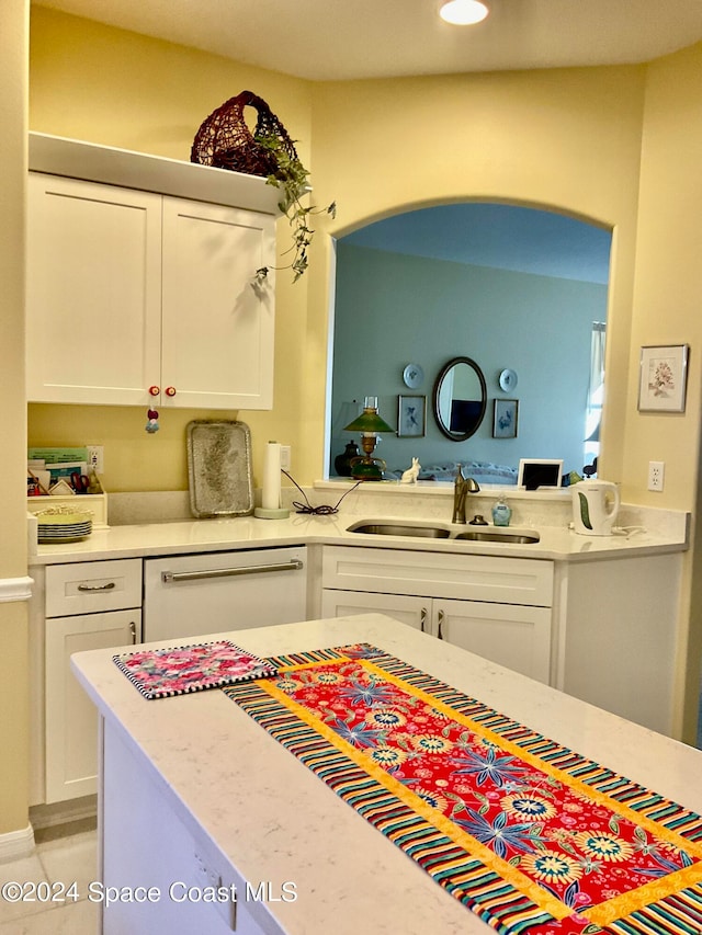 kitchen with white dishwasher, sink, and white cabinets