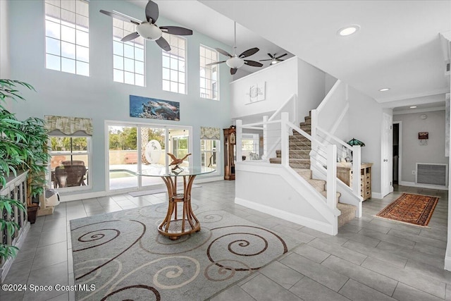 entryway featuring plenty of natural light, ceiling fan, and a towering ceiling