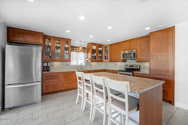 kitchen featuring a breakfast bar, stainless steel appliances, sink, decorative light fixtures, and a center island