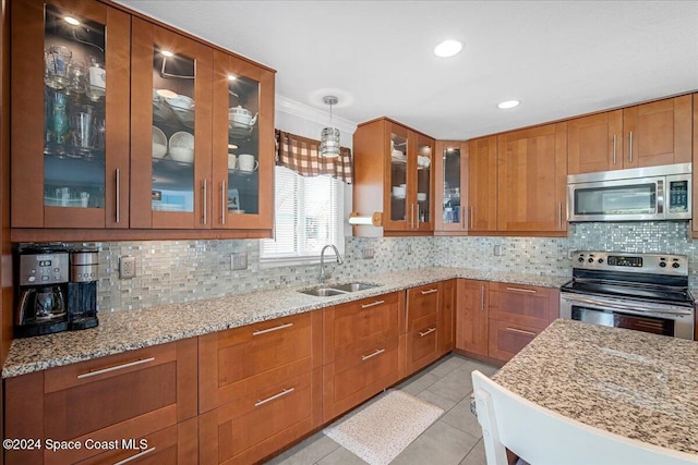 kitchen with tasteful backsplash, stainless steel appliances, sink, pendant lighting, and light tile patterned floors