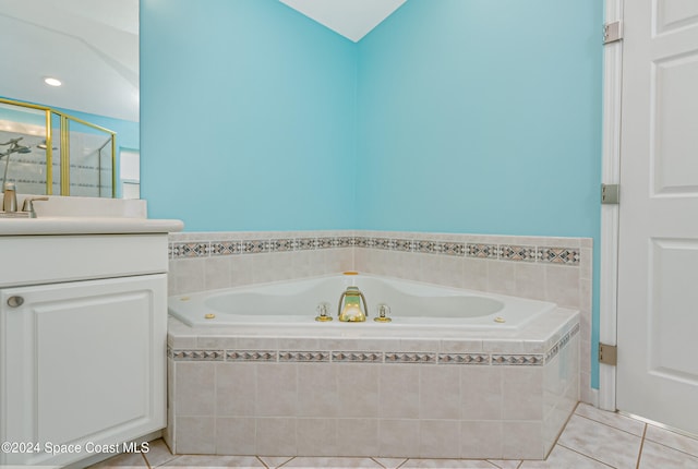 bathroom featuring vanity, vaulted ceiling, tiled tub, and tile patterned flooring