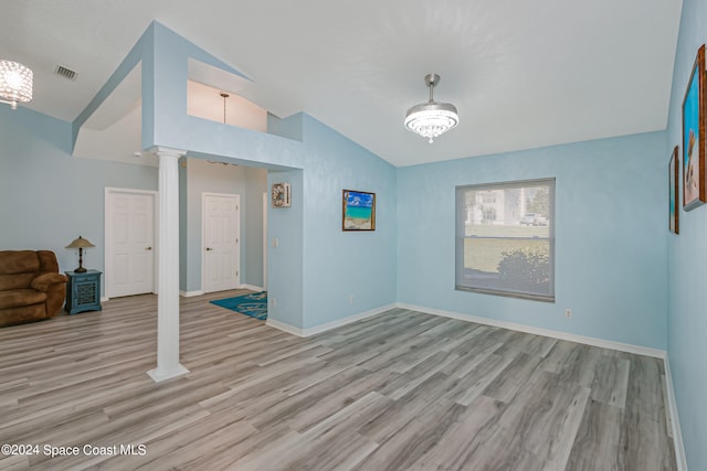 unfurnished room with light hardwood / wood-style flooring, lofted ceiling, and ornate columns