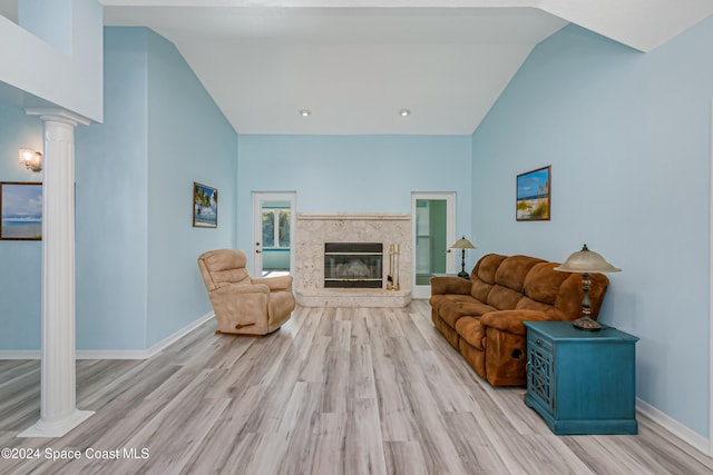 living room with light hardwood / wood-style flooring, high vaulted ceiling, and ornate columns