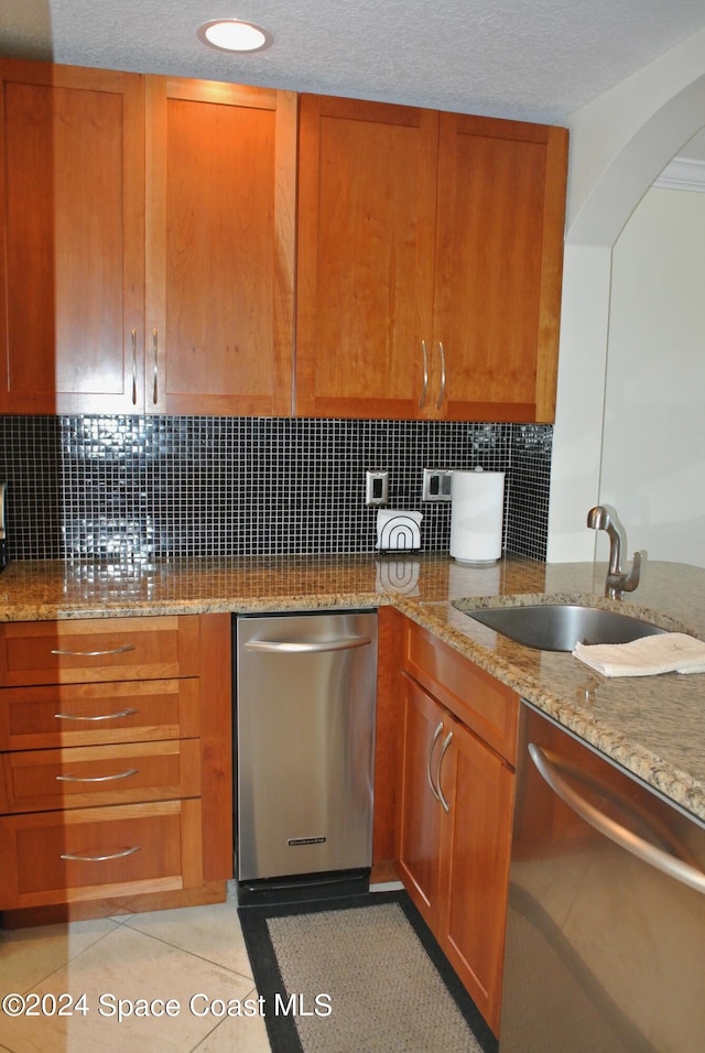 kitchen with dishwasher, light stone countertops, and a sink