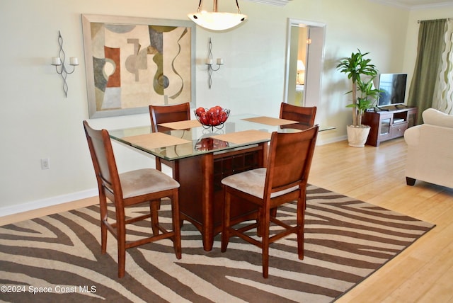 dining area with baseboards, wood finished floors, and crown molding