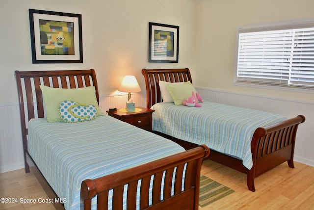 bedroom with light wood-style floors and a wainscoted wall