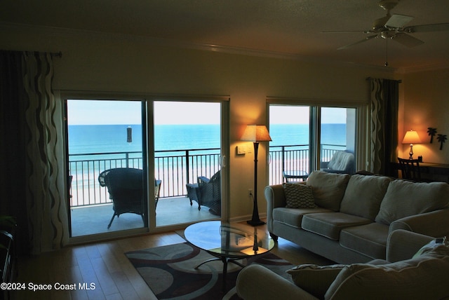 living room with a water view, ceiling fan, ornamental molding, and light hardwood / wood-style flooring