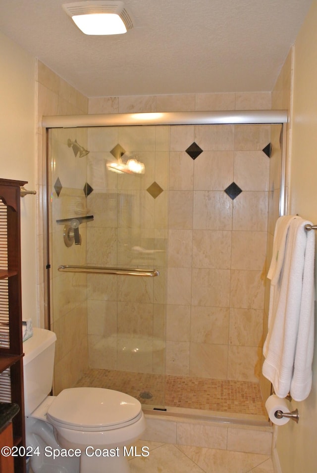 bathroom featuring a shower with door, toilet, and tile patterned flooring