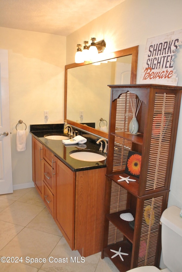 bathroom with toilet, vanity, and tile patterned floors