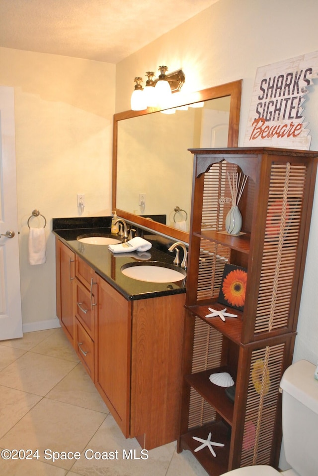 bathroom with toilet, tile patterned floors, a sink, and double vanity