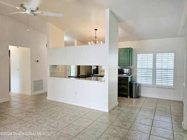 kitchen with pendant lighting, ceiling fan with notable chandelier, high vaulted ceiling, and green cabinetry