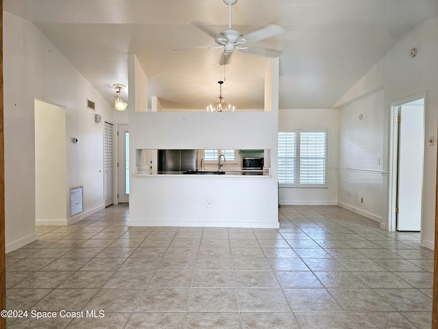 unfurnished living room with ceiling fan with notable chandelier, high vaulted ceiling, and light tile patterned flooring