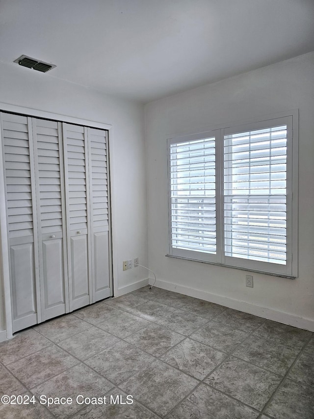 unfurnished bedroom with tile patterned floors and a closet