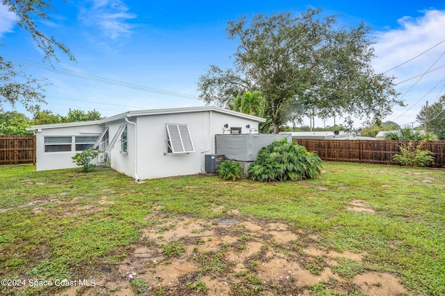 154 21st St SW, Vero Beach, FL 32962 - rear view of house featuring fence, central AC unit, a yard, and stucco siding
