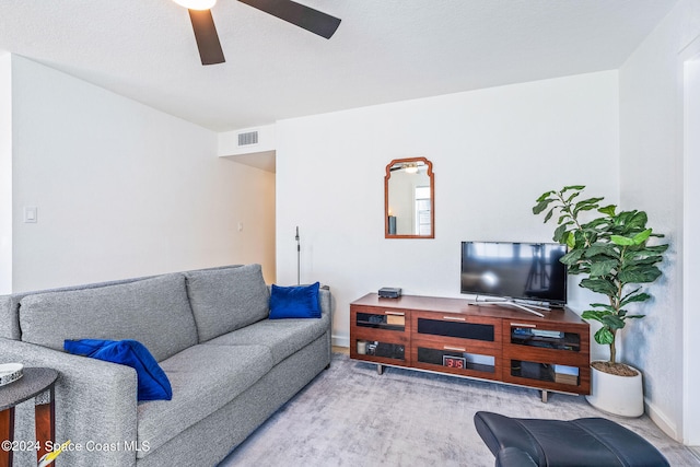 carpeted living room with a textured ceiling and ceiling fan