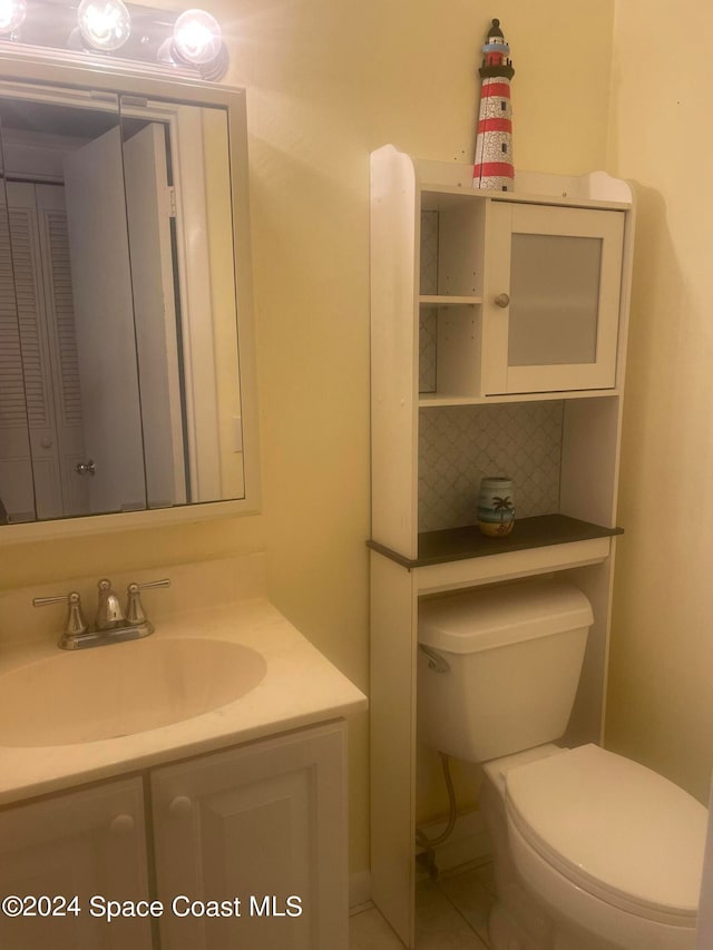 bathroom featuring vanity, toilet, tile patterned floors, and decorative backsplash