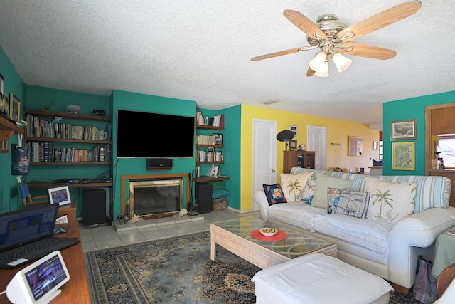 living room featuring ceiling fan, a textured ceiling, and tile patterned flooring