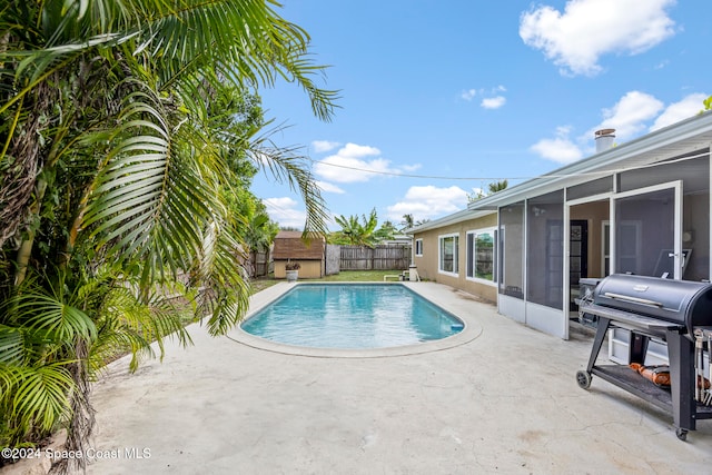 view of swimming pool featuring a grill, a patio, and a sunroom