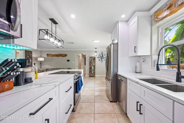 kitchen with white cabinets, light stone counters, sink, pendant lighting, and stainless steel appliances