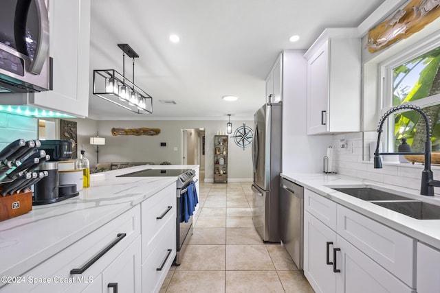 kitchen with light stone counters, white cabinetry, stainless steel appliances, and a sink