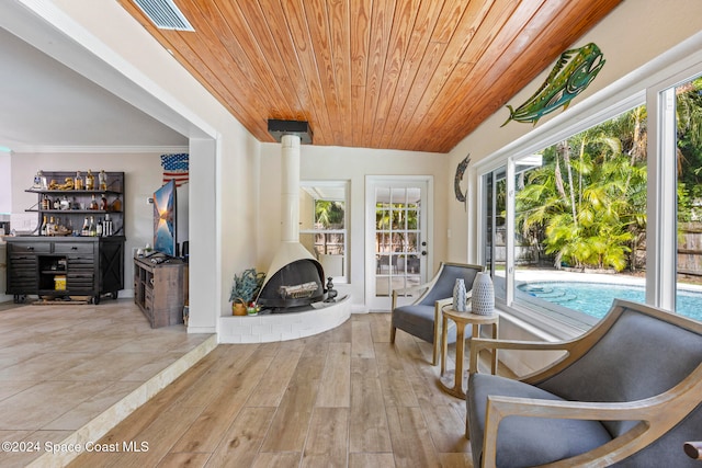 sitting room with crown molding, light wood-type flooring, and wooden ceiling