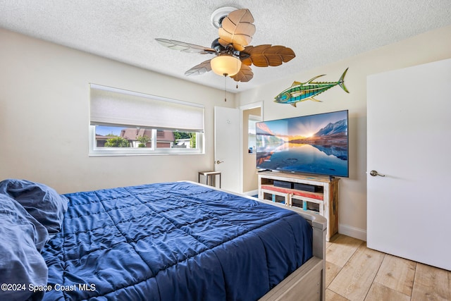 bedroom with light hardwood / wood-style flooring, a textured ceiling, and ceiling fan