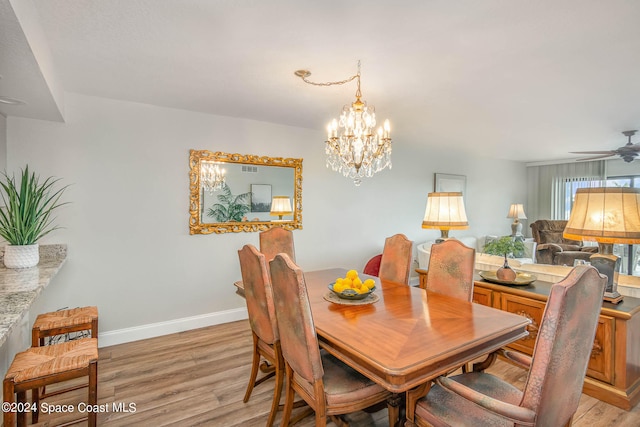 dining space with light hardwood / wood-style flooring and ceiling fan with notable chandelier