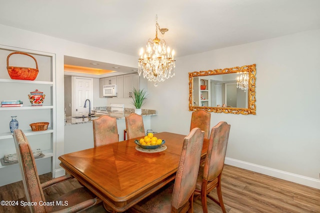 dining space featuring baseboards, a chandelier, and wood finished floors