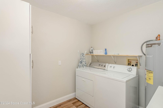 laundry room with laundry area, washer and dryer, electric water heater, light wood-style flooring, and baseboards