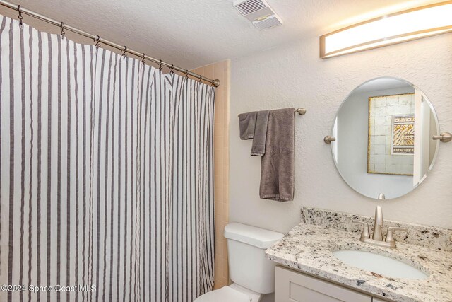 bathroom featuring toilet, a shower with curtain, vanity, a textured ceiling, and visible vents