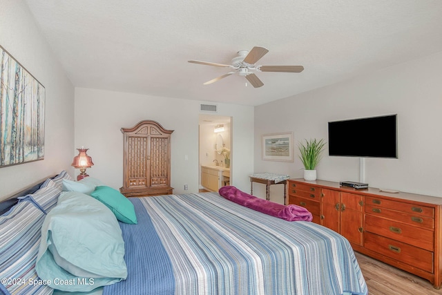 bedroom with light wood finished floors, connected bathroom, visible vents, and a ceiling fan
