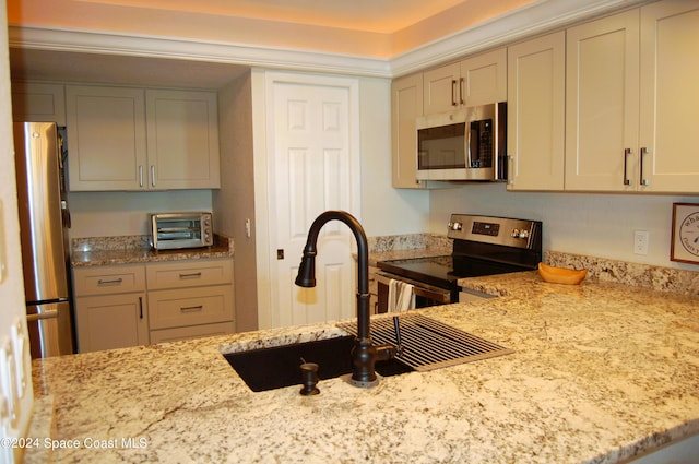 kitchen featuring light stone countertops, appliances with stainless steel finishes, and sink