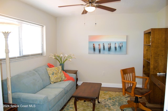 living room with baseboards, a ceiling fan, and wood finished floors