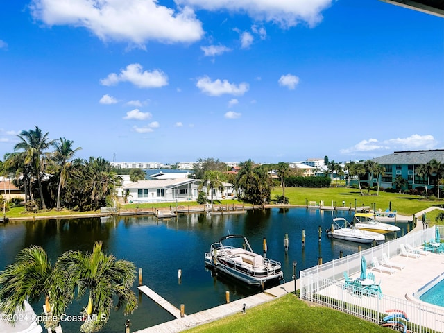 view of dock with a community pool, a yard, a water view, and fence