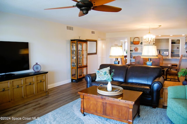 living room with dark wood-type flooring and ceiling fan with notable chandelier