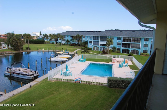 view of pool with a lawn and a water view