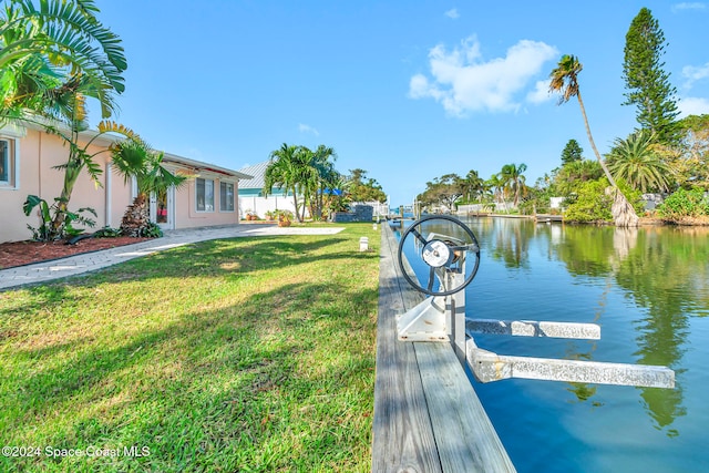 view of dock with a yard and a water view