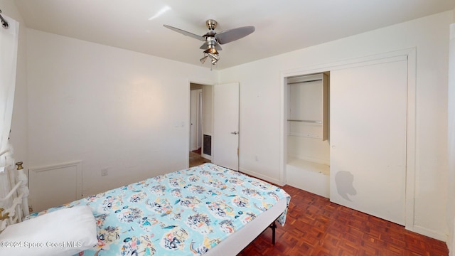 bedroom featuring ceiling fan, a closet, and dark parquet floors