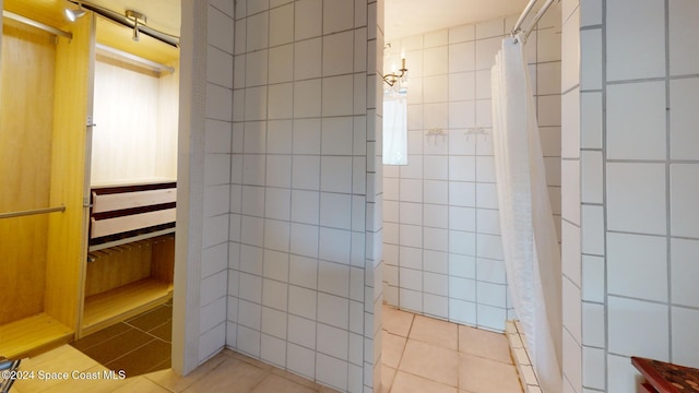 bathroom with a shower with curtain, tile patterned flooring, and tile walls