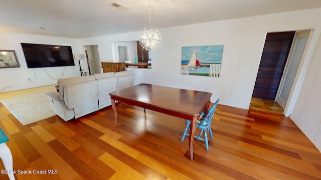 dining space with hardwood / wood-style flooring and a notable chandelier