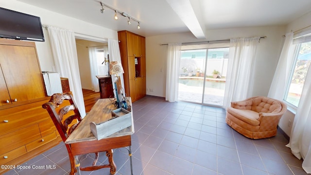 sitting room featuring beamed ceiling, radiator heating unit, light tile patterned floors, and a wealth of natural light