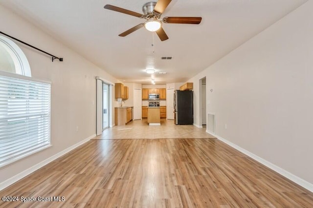 unfurnished living room featuring light hardwood / wood-style flooring and ceiling fan