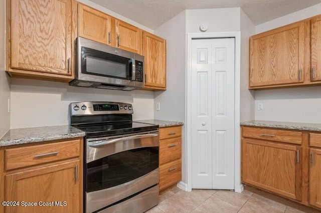 kitchen featuring light stone counters, appliances with stainless steel finishes, and light tile patterned floors