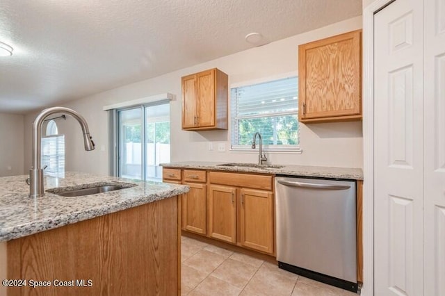 kitchen with light stone counters, sink, and stainless steel dishwasher