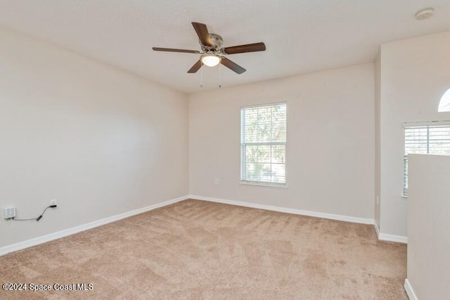 spare room featuring a wealth of natural light, light carpet, and ceiling fan